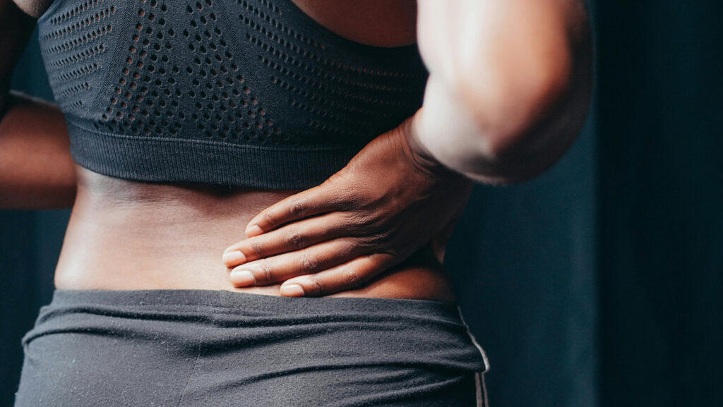 Young woman holding her lower back as she is in pain