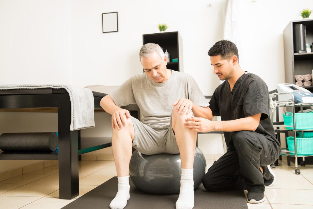 Chiropractor doing some Arthritis tests on a male patient using a exercise ball