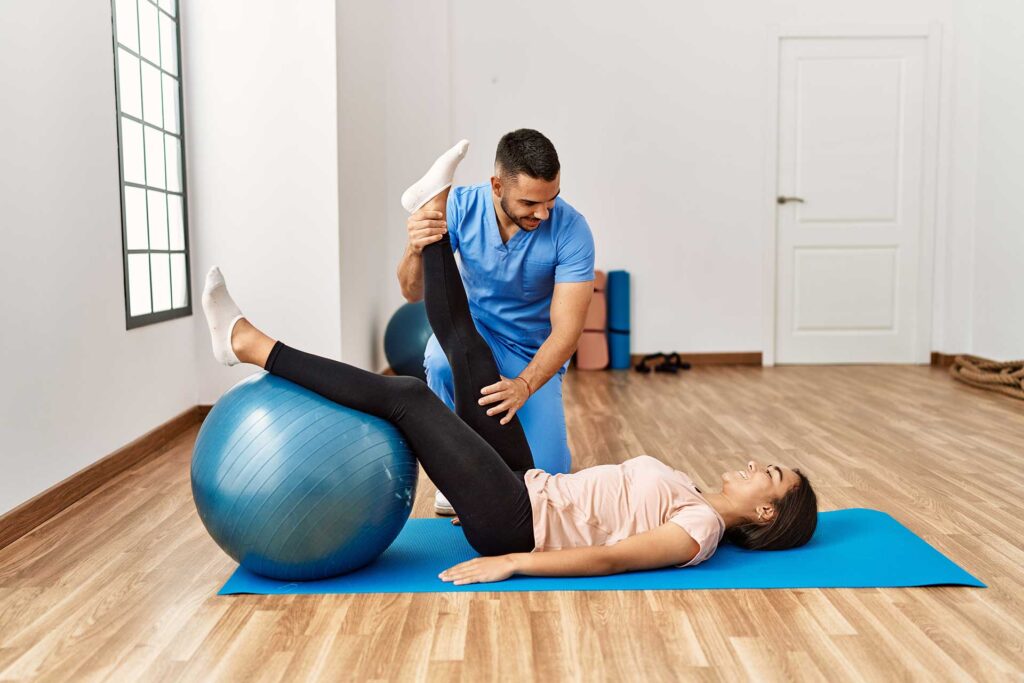 Chiropractor doing some stretches with patient using an exercise ball